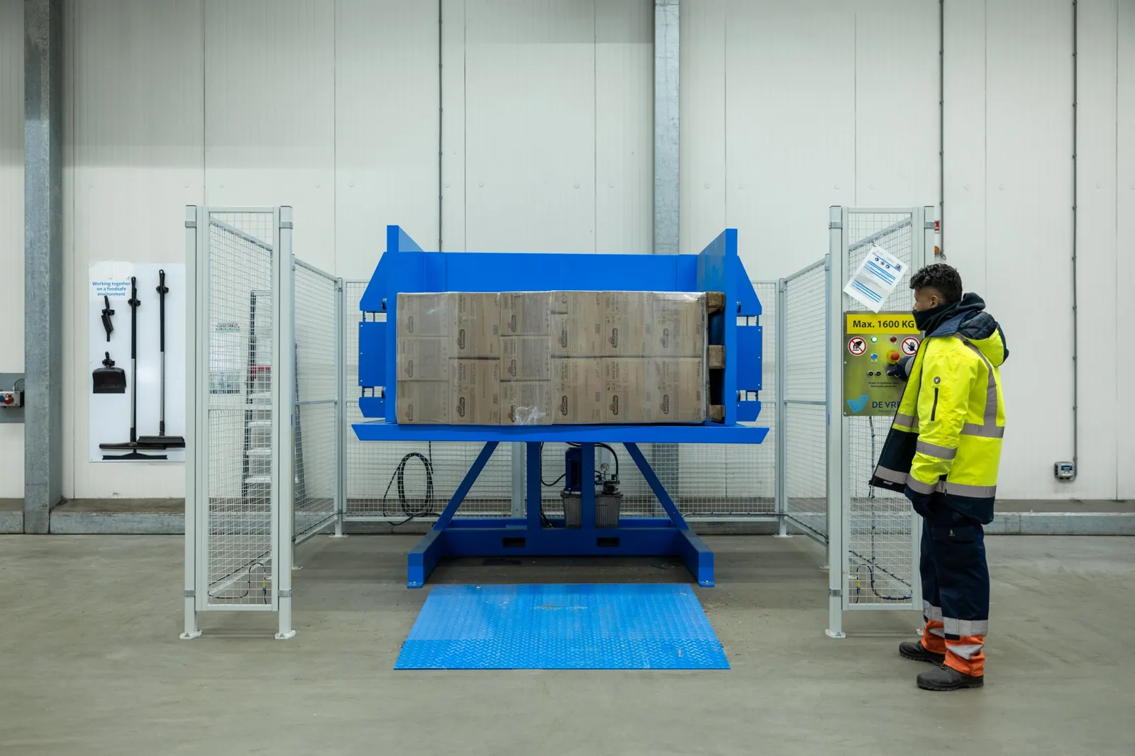 Volteador de palets PalletRotator EPT con palé volcado y operario junto al panel de control