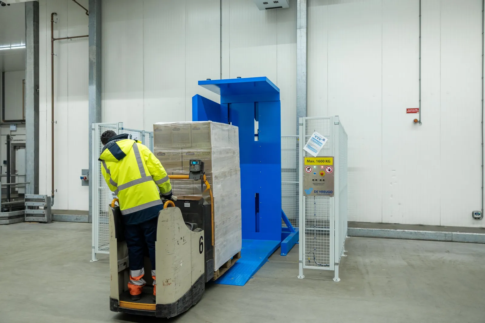 Un operario sube con una transpaleta eléctrica y un palé por la rampa del volteador de palets PalletRotator EPT